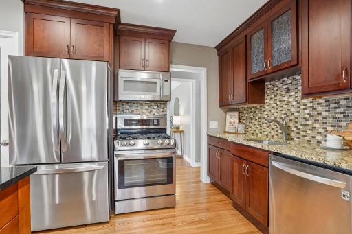 Premium stainless steel appliances include a new refrigerator (December 2025), beautifully complemented by rich wood cabinetry and granite countertops