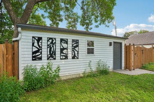 A distinctive four-panel art installation on the two-car garage adds a unique touch of architectural character to the backyard setting