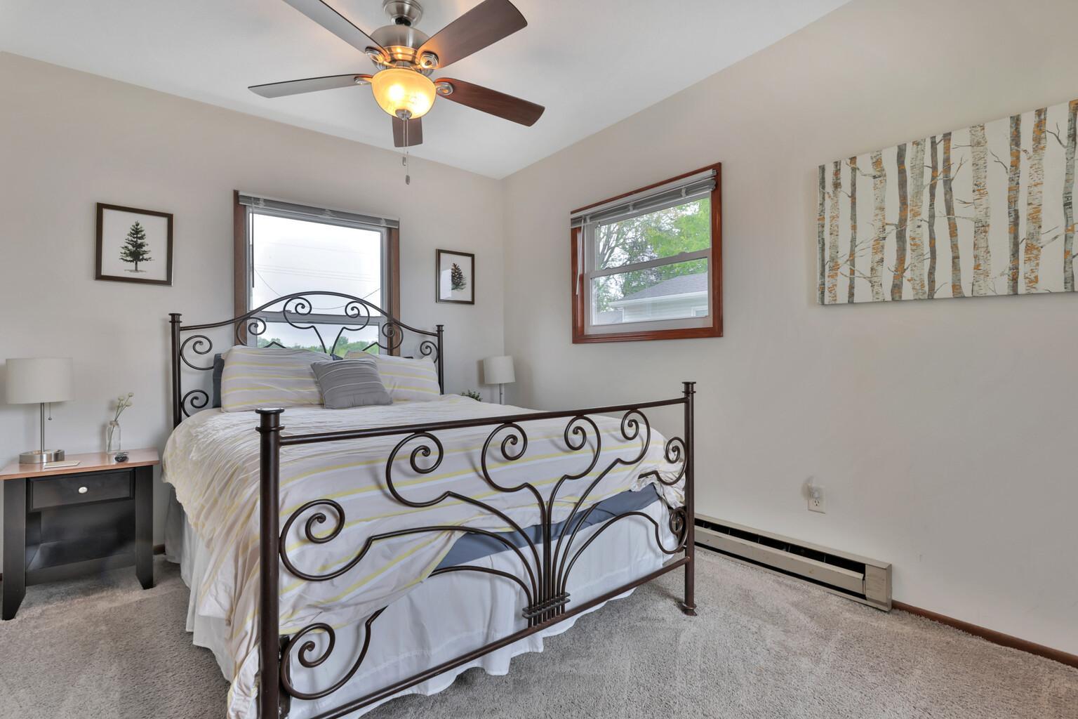 Larger of the two bedrooms with ceiling fan and view of the lake (opposite side of room. Ceiling fan and additional baseboard heat.
