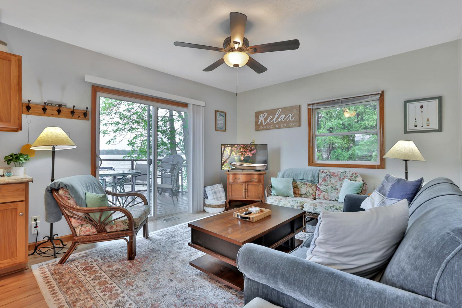Living room with ceiling fan and patio door to lakeside deck.