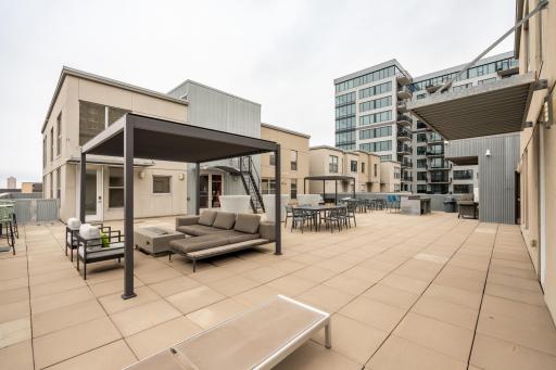 Incredible rooftop deck offers entertaining space with multiple lounge areas, dining setups, grilling station, and panoramic downtown skyline views.
