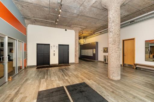 Dramatic lobby features soaring ceilings, exposed concrete columns, industrial finishes, designer lighting, and a warm upscale feel the moment you walk in