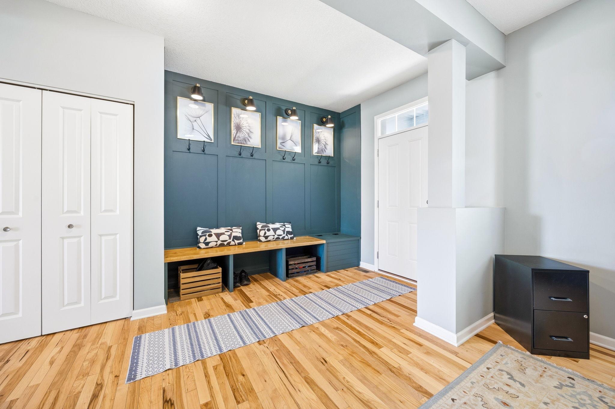 Stylish mudroom-style drop zone with custom built-in bench seating, wall hooks, and designer accent wall for everyday function and organization.