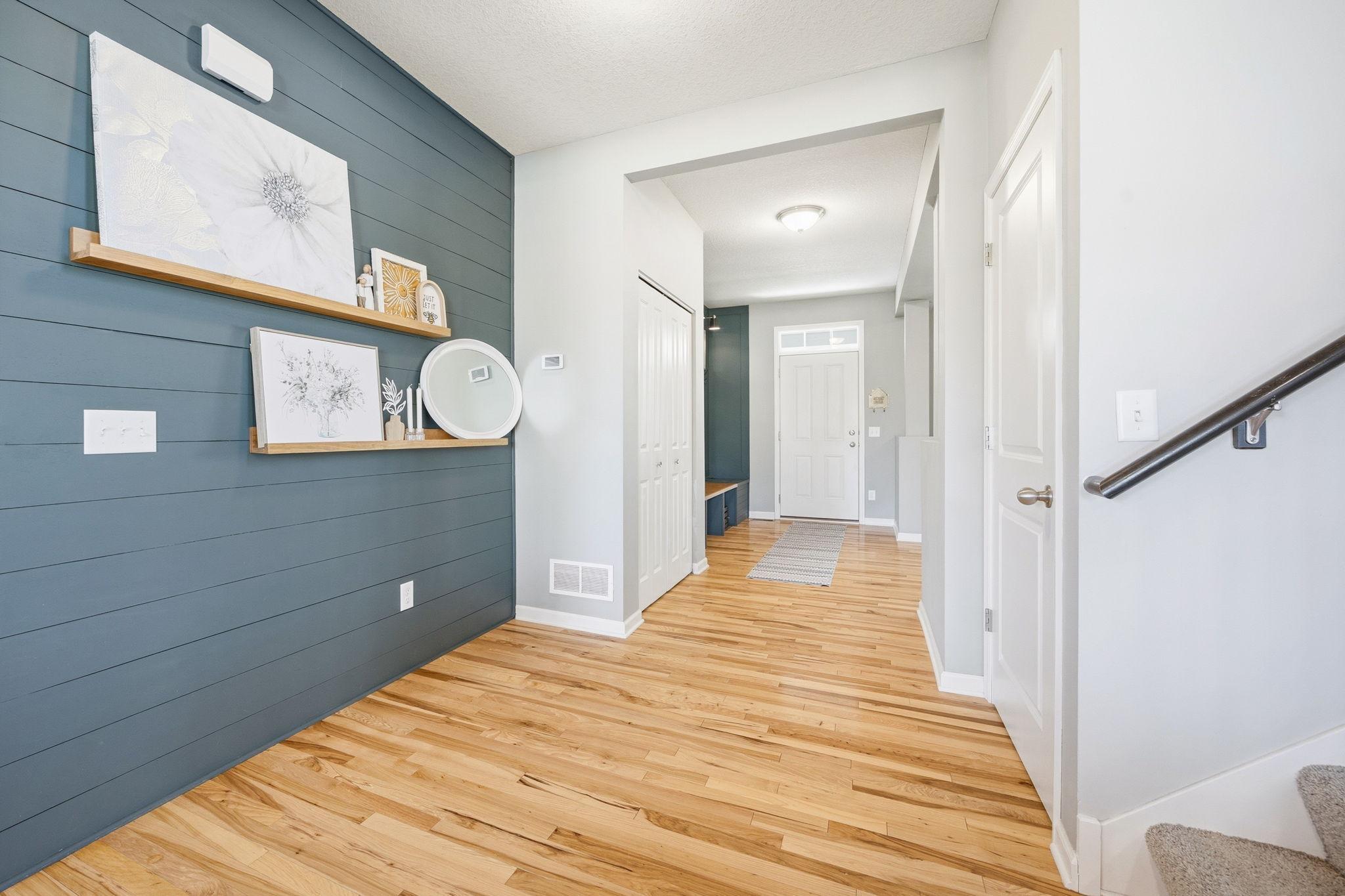 Welcoming entryway with rich hardwood floors, custom shiplap accent wall, and stylish designer details that create a warm, modern first impression.