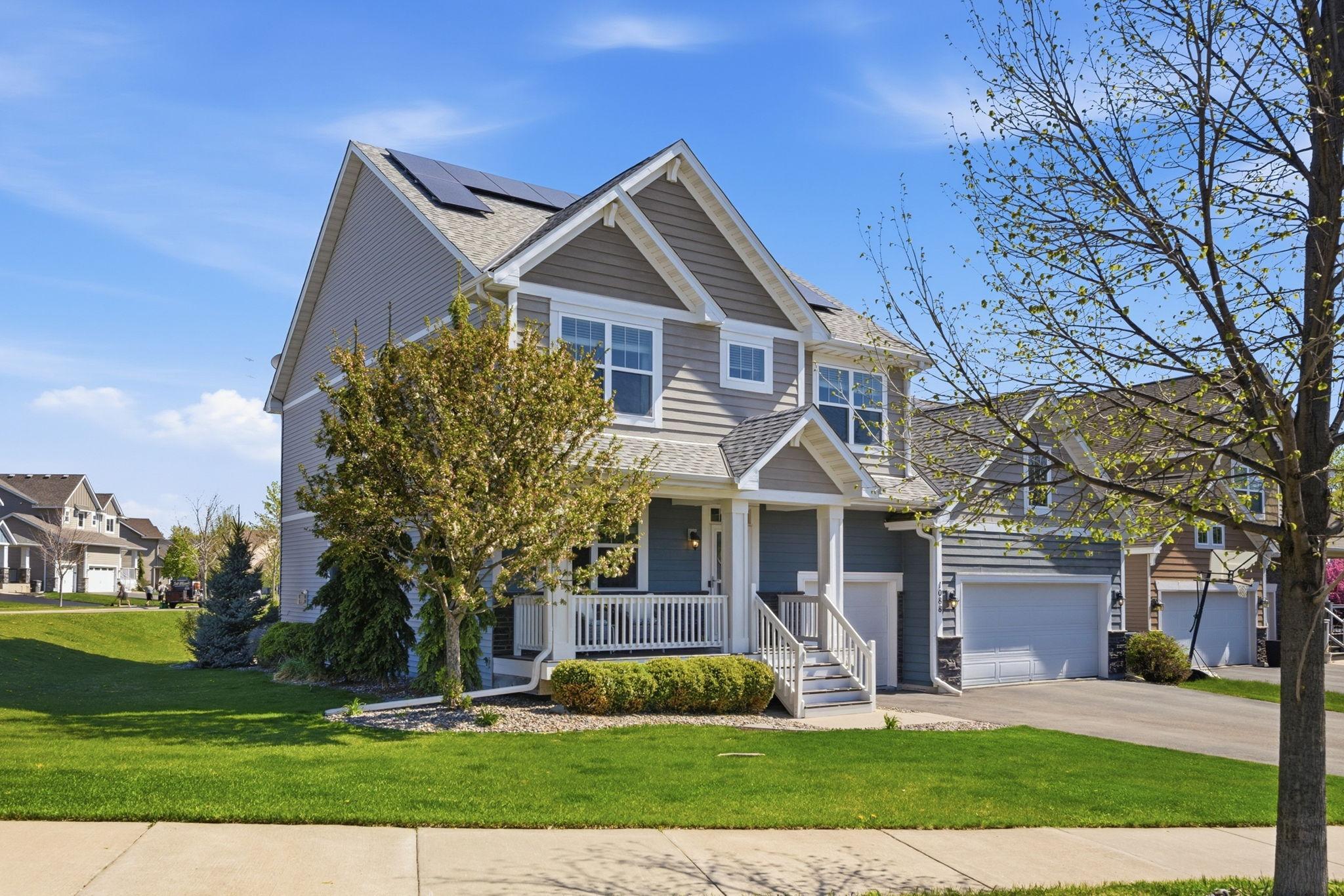 Beautiful corner-lot home with charming front porch, manicured landscaping, and energy-saving solar panels, offering standout curb appeal in a desirable neighborhood setting.