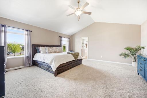 Spacious primary suite featuring vaulted ceilings, oversized windows, plush carpeting, and plenty of room for a sitting area or private retreat.