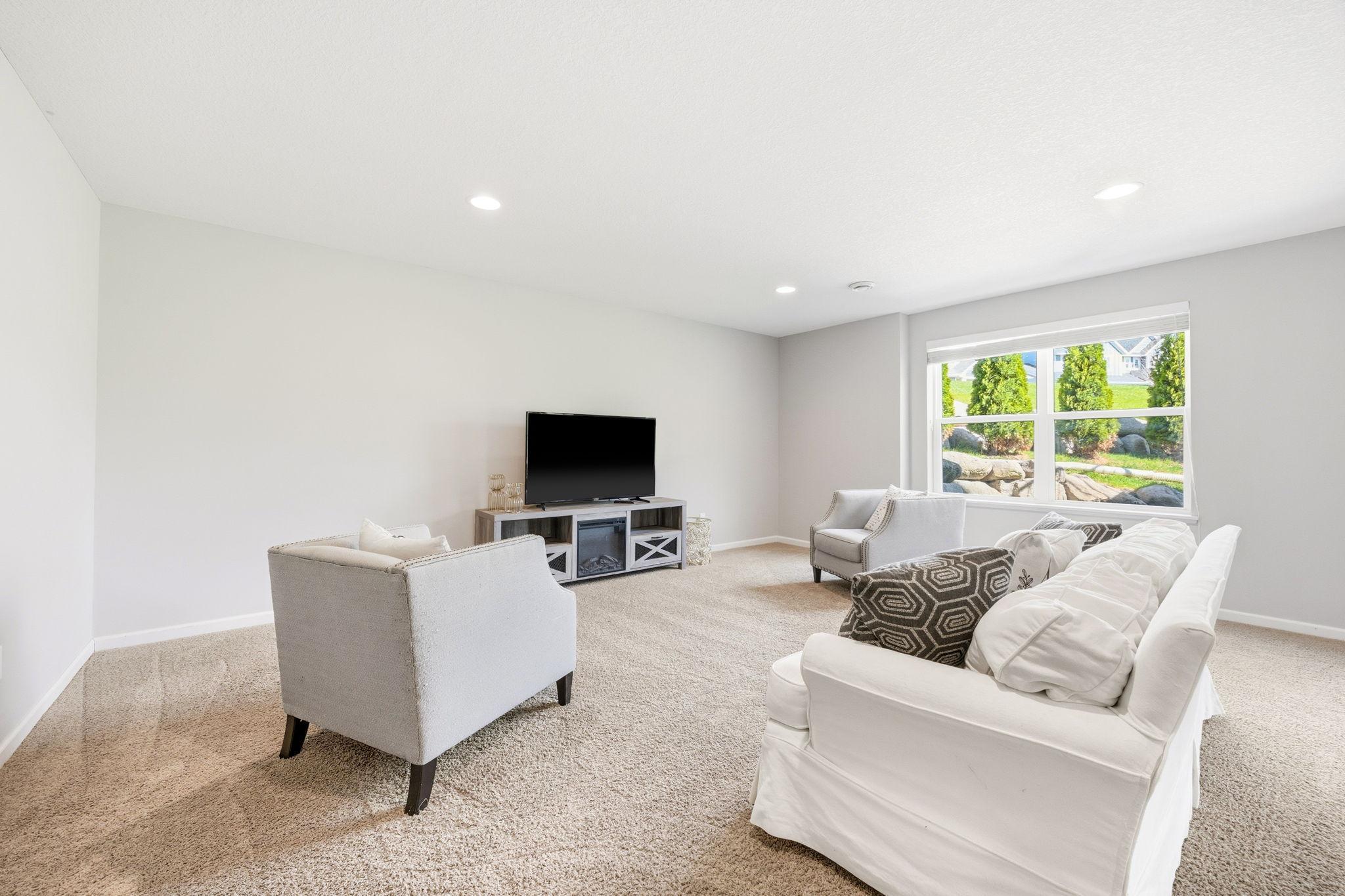 Spacious finished lower-level family room with recessed lighting, large lookout windows, and versatile open space perfect for movie nights, gaming, or entertaining.