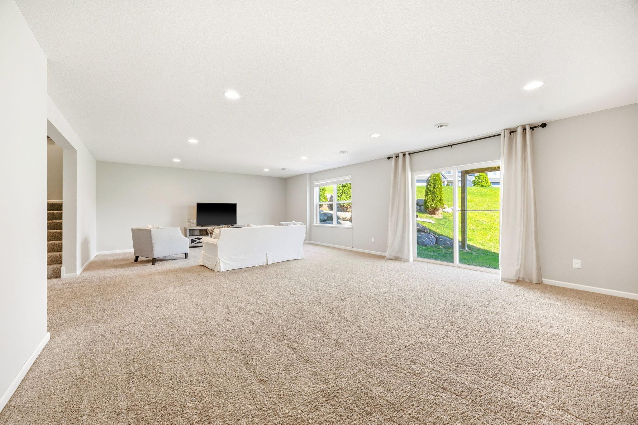 Expansive finished walkout lower level with oversized family room, abundant natural light, and flexible space ideal for entertaining, recreation, fitness, or future game areas.