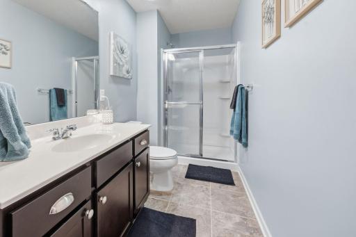 Finished lower-level bathroom with walk-in shower, oversized vanity, and neutral finishes provides added convenience for guests and entertaining.
