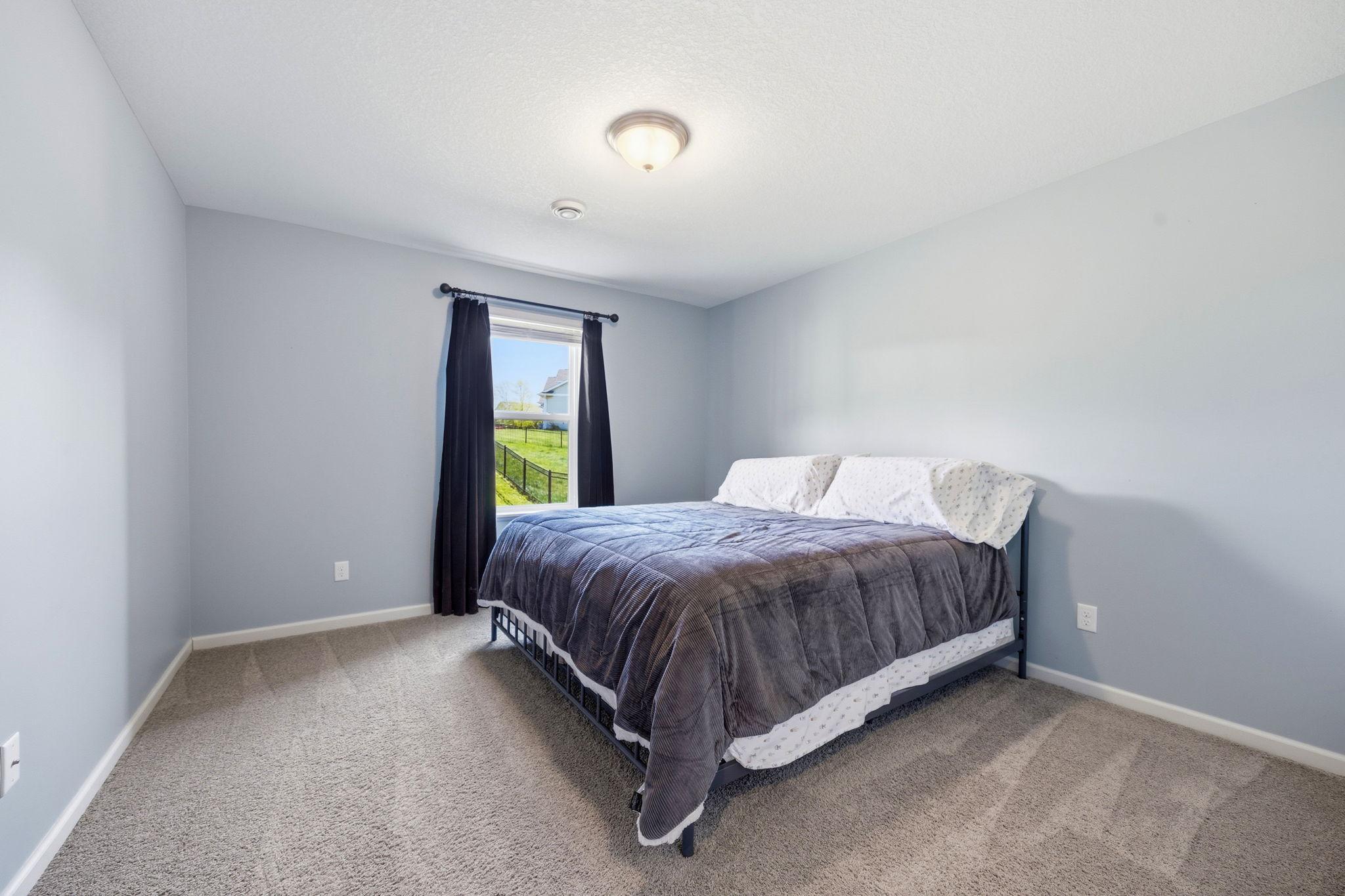 Spacious lower-level bedroom with plush carpeting, large window for natural light, and flexible space ideal for guests, teens, or a private home office.