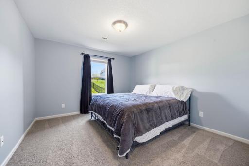 Spacious lower-level bedroom with plush carpeting, large window for natural light, and flexible space ideal for guests, teens, or a private home office.