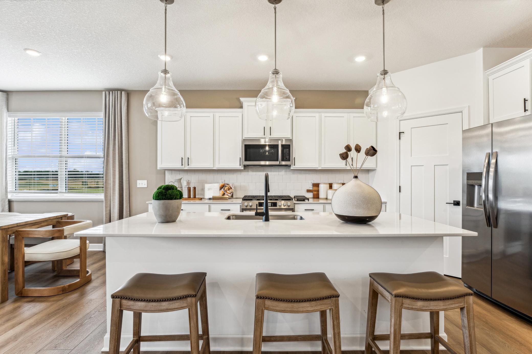 (Photo of a decorated model, actual homes finishes will vary) The stunning kitchen features a large center island, quartz countertops, LVP floors, stainless appliances and more!