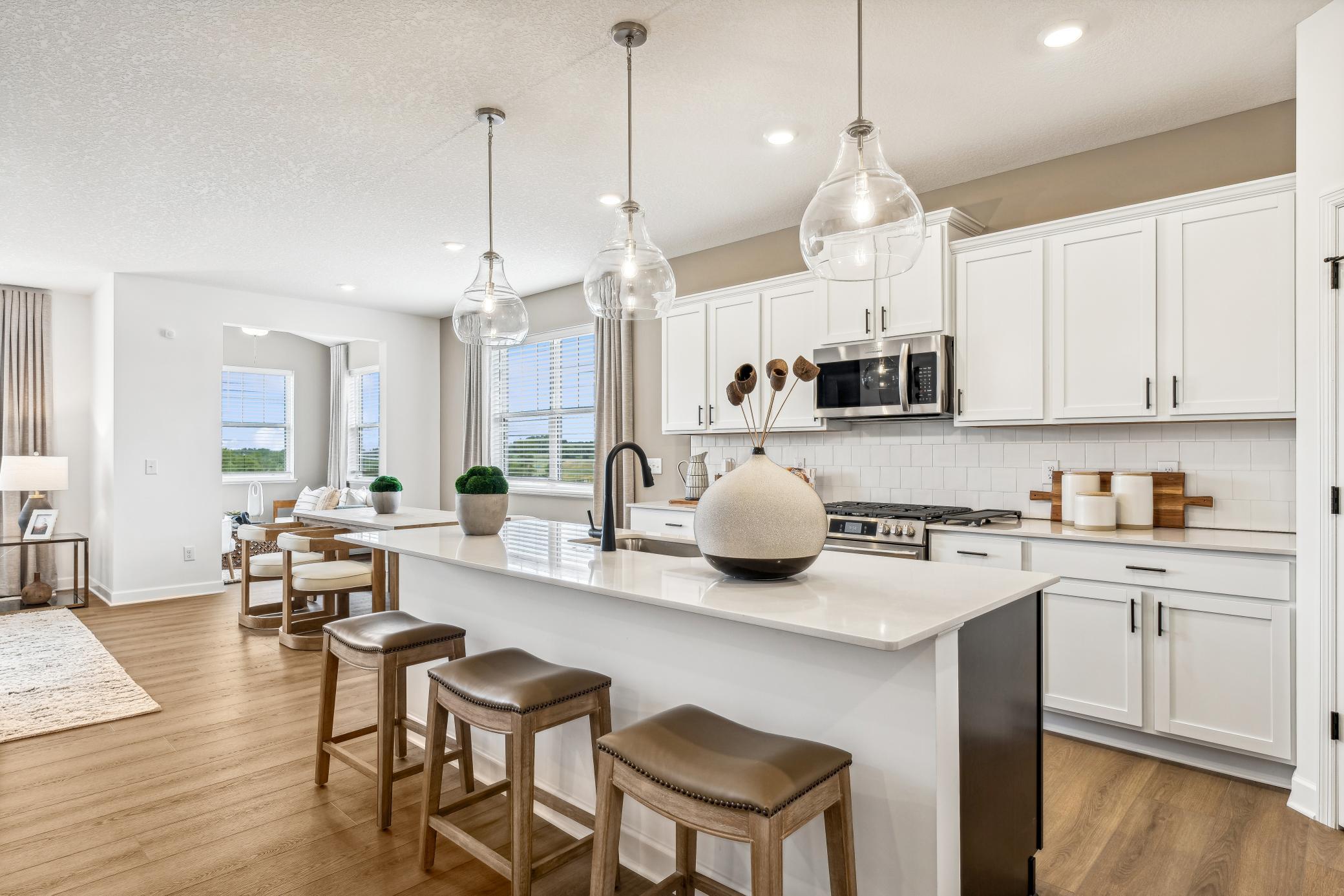 (Photo of a decorated model, actual homes finishes will vary) The kitchen island overlooks the dining area.