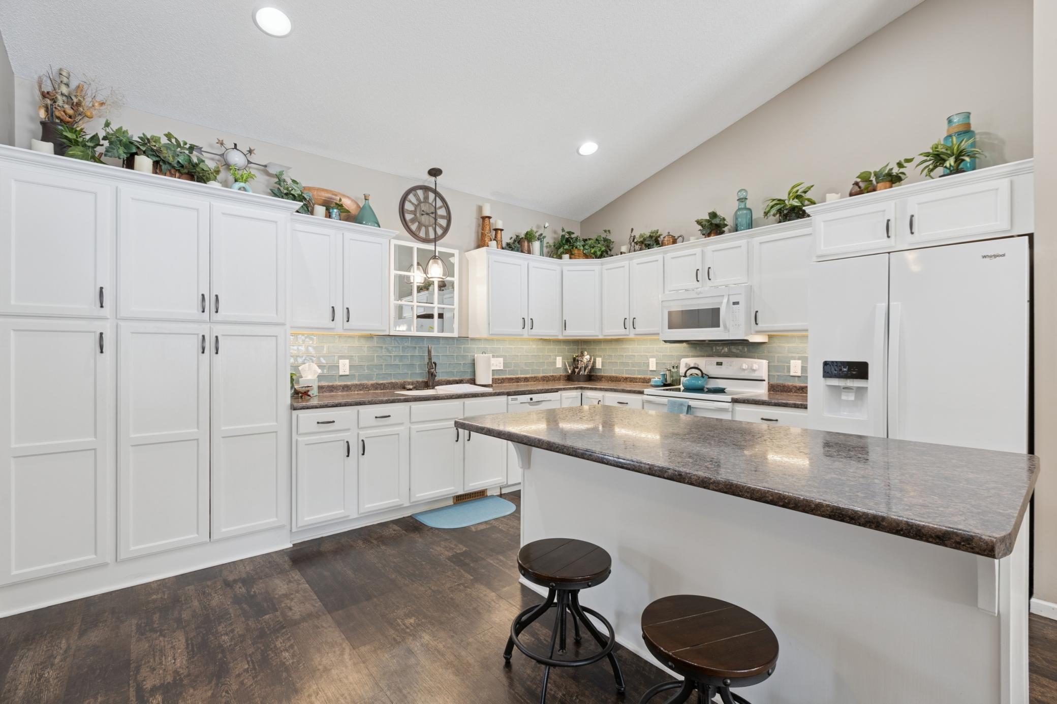 The spacious kitchen has an abundance of cabinets with pull out drawers, and storage space. The tile backsplash compliments the cabinets.