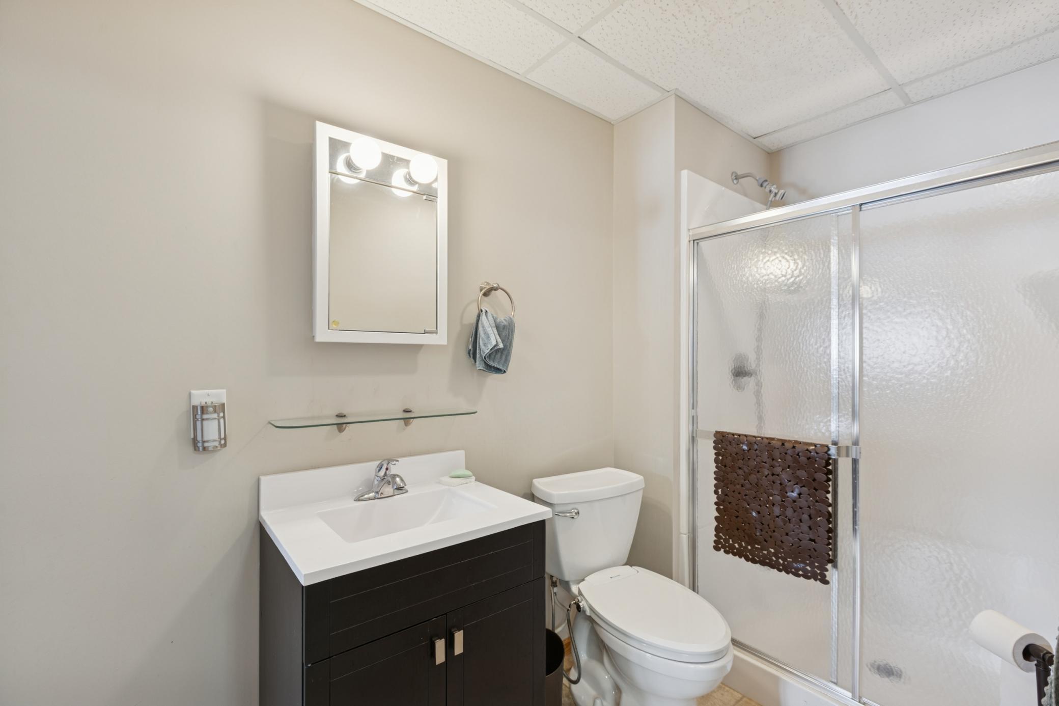 The 3/4 bathroom in the lower level has a vanity, toilet, shower and tiled floors.