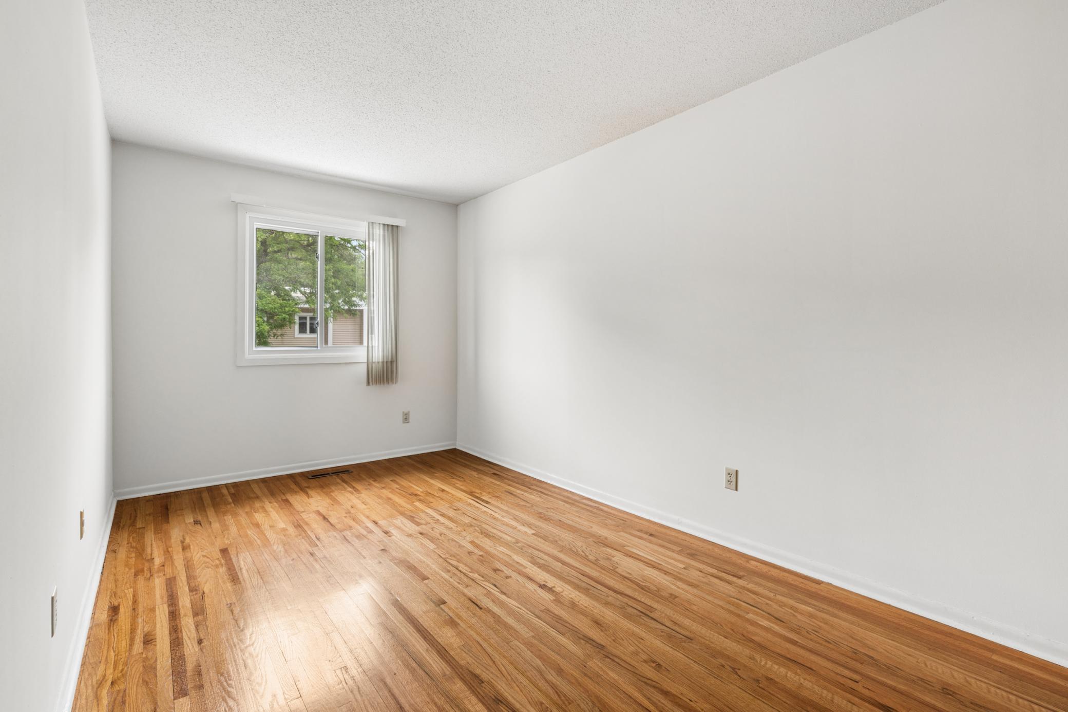 Primary bedroom with gleaming hard surface floors, neutral tones, and abundant natural light!