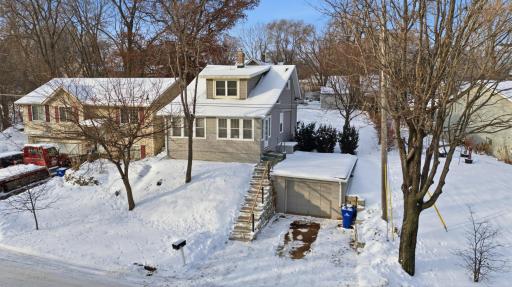 Front of home with one stall attached garage that leads into the unfinished basement. Sellers had the exterior stairs redone and installed a retaining wall behind where the garbage cans sit.