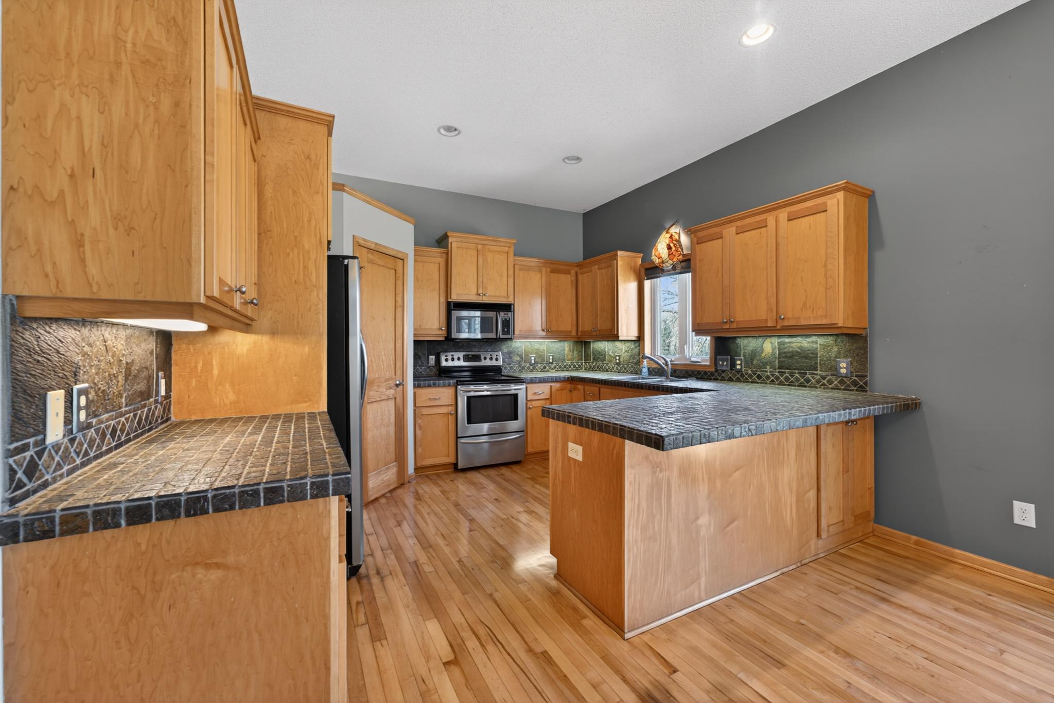 Beautiful kitchen features slate tile countertops and a breakfast bar!
