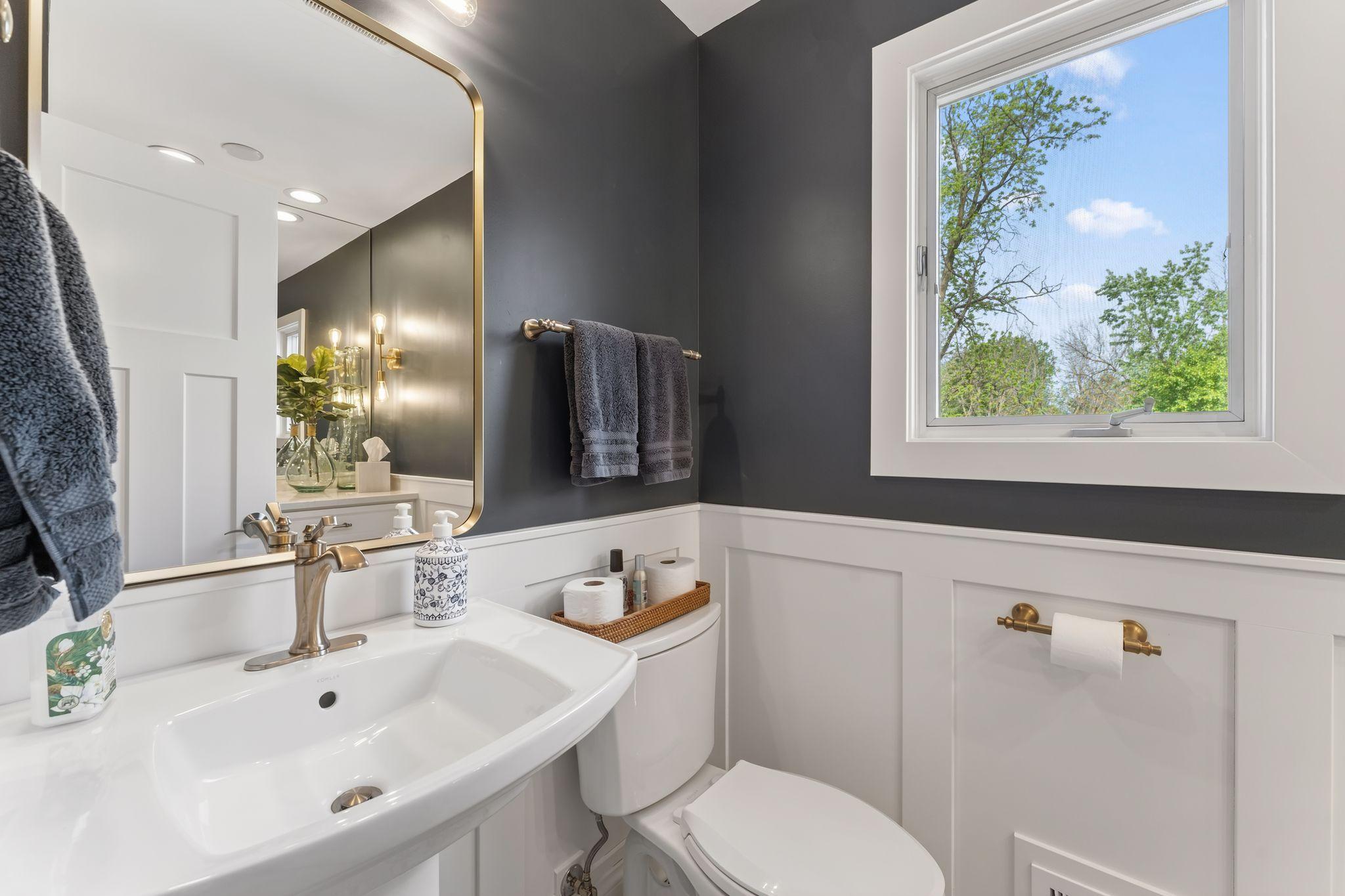 The main floor powder room with custom wainscoting millworker, a pedestal sink and tile flooring - all recently updated.