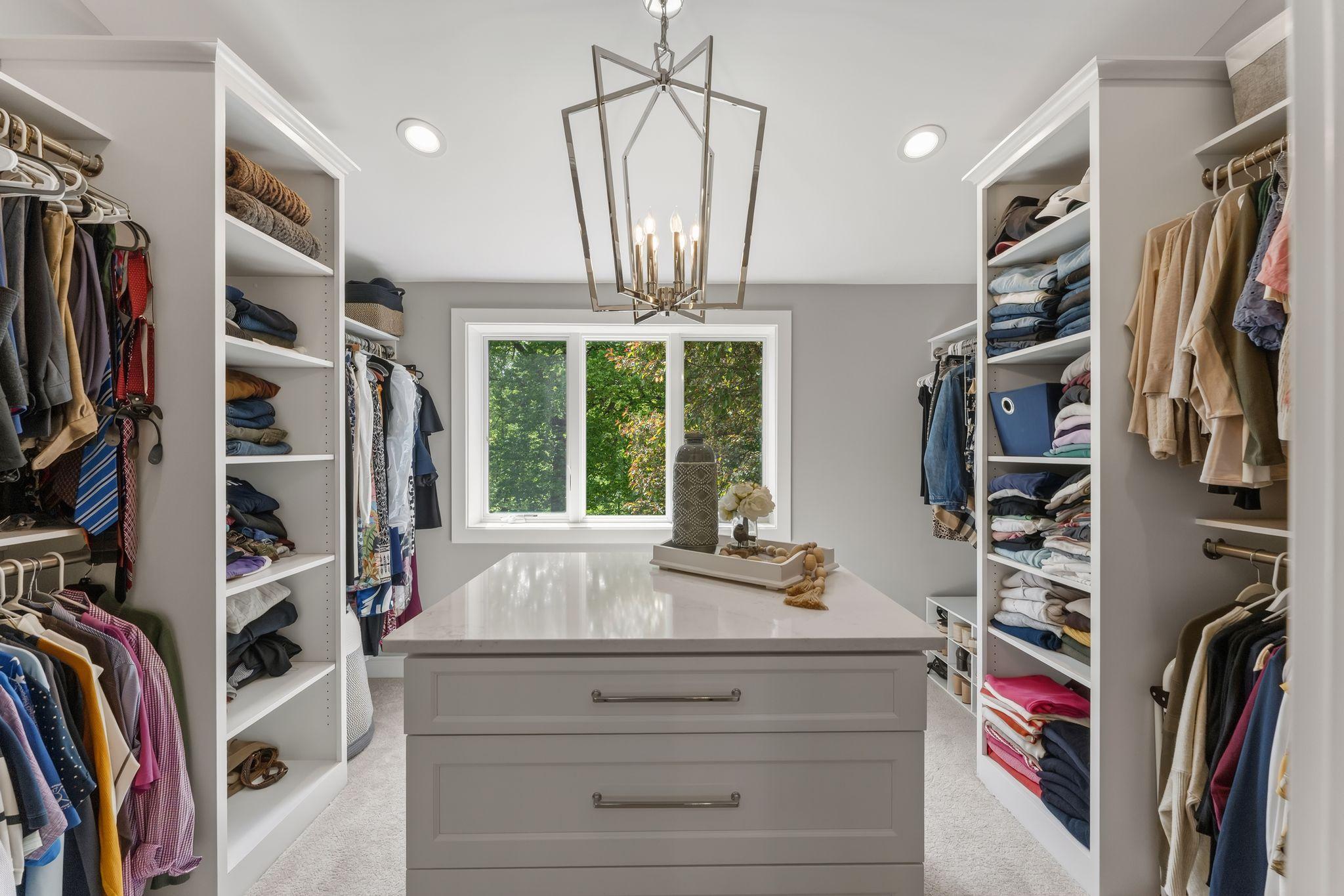 There are walk in closets...and then this happens!! An island with a quartz counter top, drawer for days, custom closet shelving, floor to ceiling storage and a statement chandelier tying it all together!
