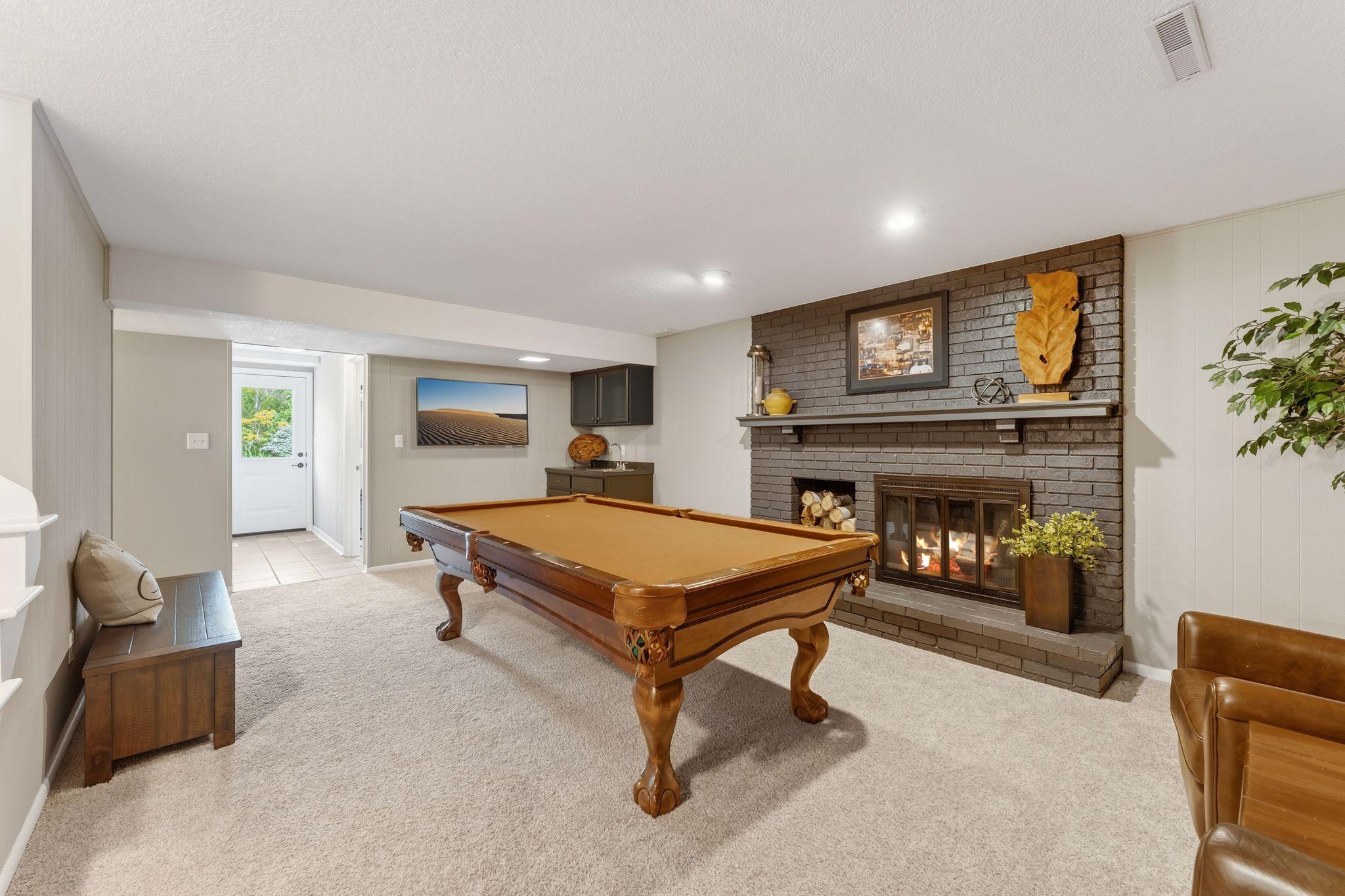 The lower level amusement room with its sharp looking brick, wood burning fireplace