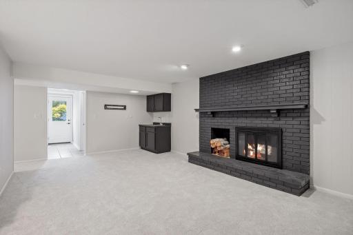 The lower level amusement room with its sharp looking brick, wood burning fireplace