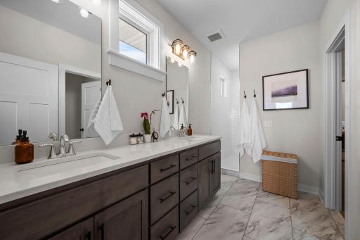Spacious primary bathroom with tile floors, double vanity and walk-in shower