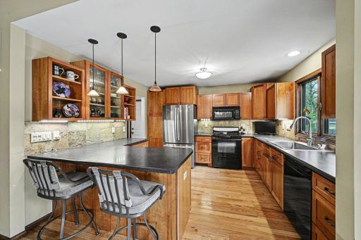Natural stone backsplash, under cabinet lighting, stainless refrigerator with water filtration system, glass display cabinets and large pantry cabinet.