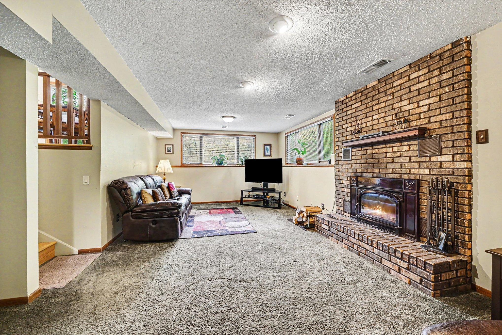 Lower level has nice look out windows with shades to darken the room to cozy up to the fireplace.