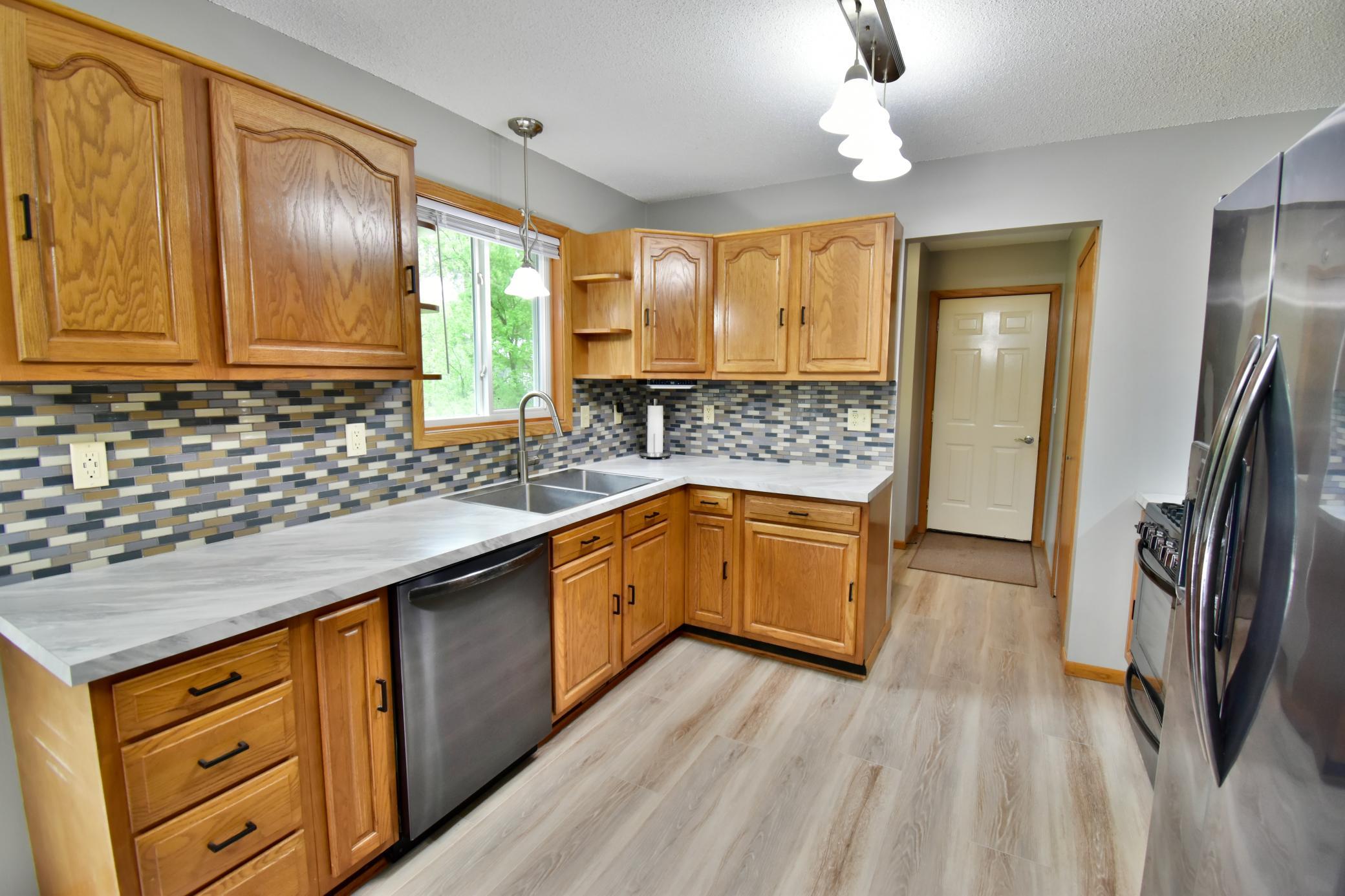 New countertops, backsplash and LVP flooring make this space so appealing. The access to the garage and laundry room are located just on the other side of the back wall of the kitchen.