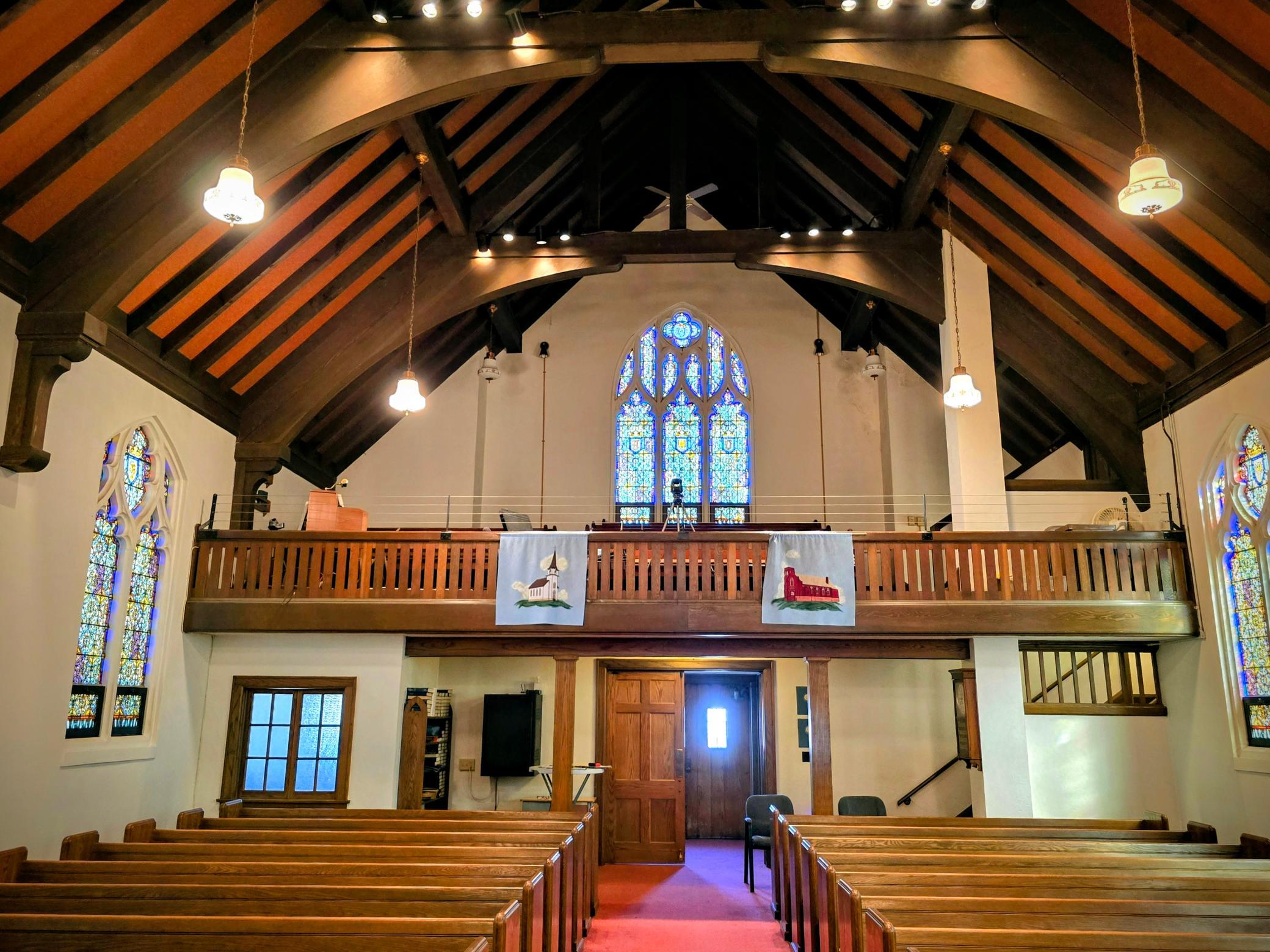 “Beautiful upper balcony overlooking the sanctuary provides additional seating and showcases the stunning wood craftsmanship, soaring ship-hull style ceiling, and breathtaking stained-glass windows.