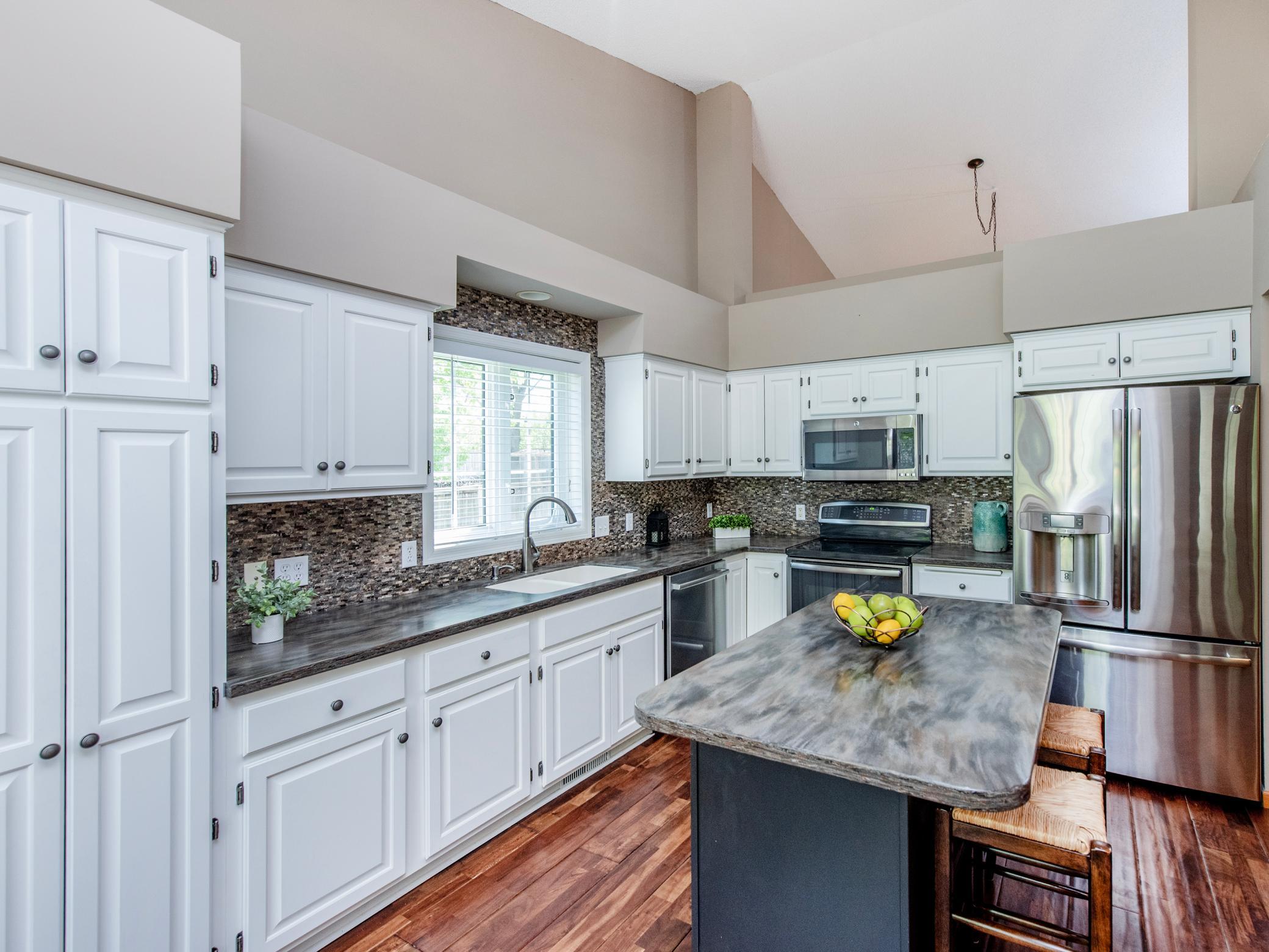 Functional and updated kitchen featuring abundant storage, stainless steel appliances, and a tile backsplash.