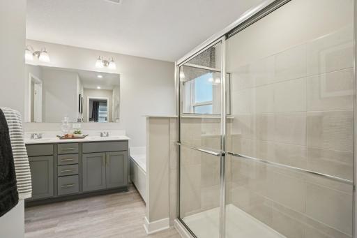 Beautifully tiled walk-in shower and dual vanity make getting ready a little more enjoyable! Model photo, options and colors may vary.