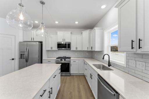 (Photo of a similar home, actual finishes may vary) The spacious kitchen features brand-new stainless steel appliances, a center island and ample cabinetry storage.