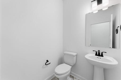 (Photo of a similar home, actual finishes may vary) The powder room is easily accessible from the communal living spaces.