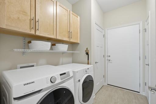 Just inside the garage entry, the laundry room offers a convenient drop zone with cabinetry and two closets, providing plenty of space to keep coats, shoes, laundry essentials.
