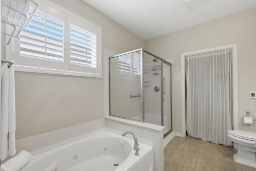 A garden soaking tub and separate shower create a relaxing retreat, complemented by plantation shutters on the transom-style window that brings natural light into the space while maintaining privacy.