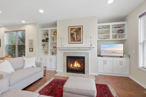 A beautiful gas fireplace creates a focal point in the living room, surrounded by white cabinetry and decorative shelving that provide both style and thoughtful display space.