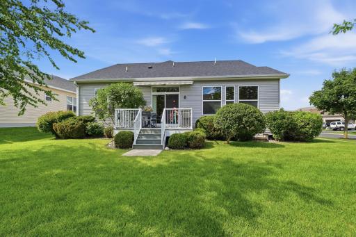 A charming maintenance free deck with a retractable awning creates a wonderful spot to relax and enjoy the outdoors, surrounded by mature greenery that adds beauty and a sense of privacy.