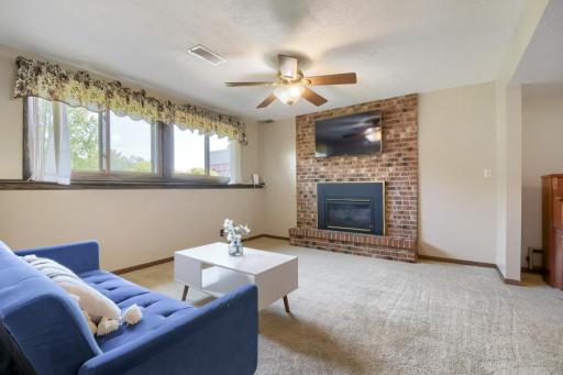 The lower-level family room with plenty of windows and light in addition the gas fireplace and brick surround! This is the perfect place to watch the big game or movie night with popcorn!