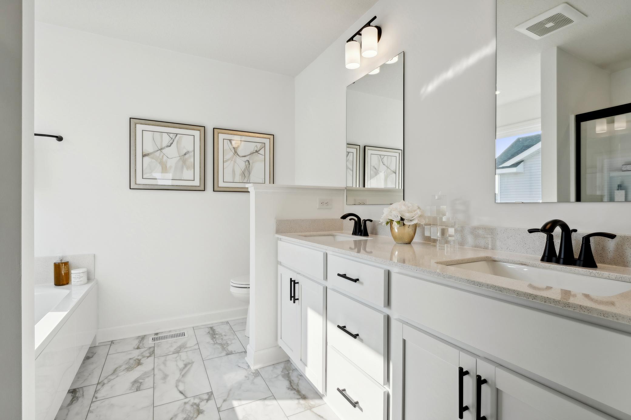(Photo of a decorated model, actual homes finishes will vary) The private primary ensuite bath offers a wonderful luxury height double vanity with a quartz counter top, a soaking tub and separate shower.