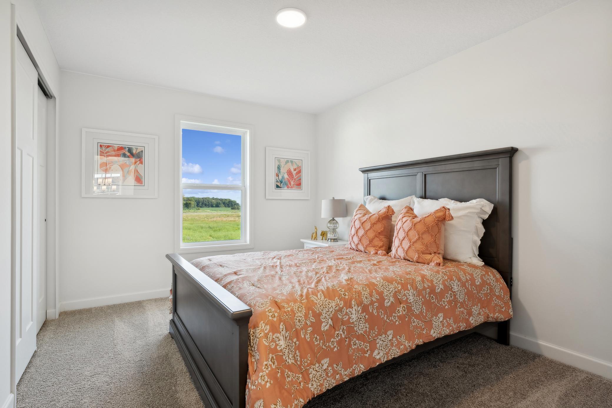 (Photo of a decorated model, actual homes finishes will vary) One of three generously sized upper level secondary bedrooms with spacious closets.