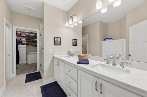 Primary bath with a double sink vanity, built-in linen cabinet, walk-in closet with access cabinet to the main floor laundry room, jewelry drawers, and organizers-