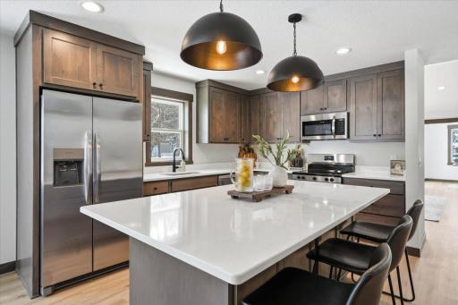 Stainless appliances and white countertops/backsplash gleam against the dark wood and countertops.