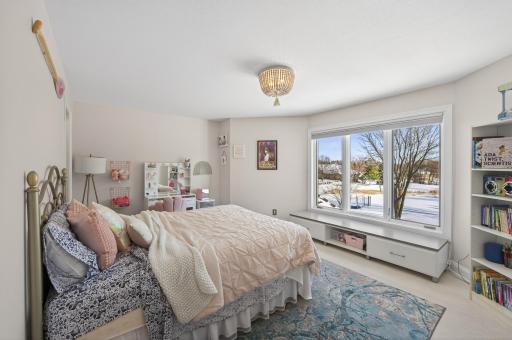 Bedroom four is also spacious and features luxury plank flooring, a large rear-facing window, a unique light fixture, and a walk-in closet with built-ins.