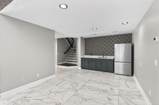 A nearby wet bar enhances the entertainment experience, complete with generous counter space, custom cabinetry, a sink, and a full-size refrigerator.