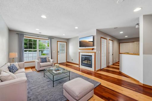 The bright and inviting family room features abundant natural light, a cozy gas fireplace, and beautiful hardwood flooring throughout.