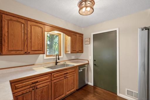 Farmer-style stainless steel sink beneath backyard-facing window