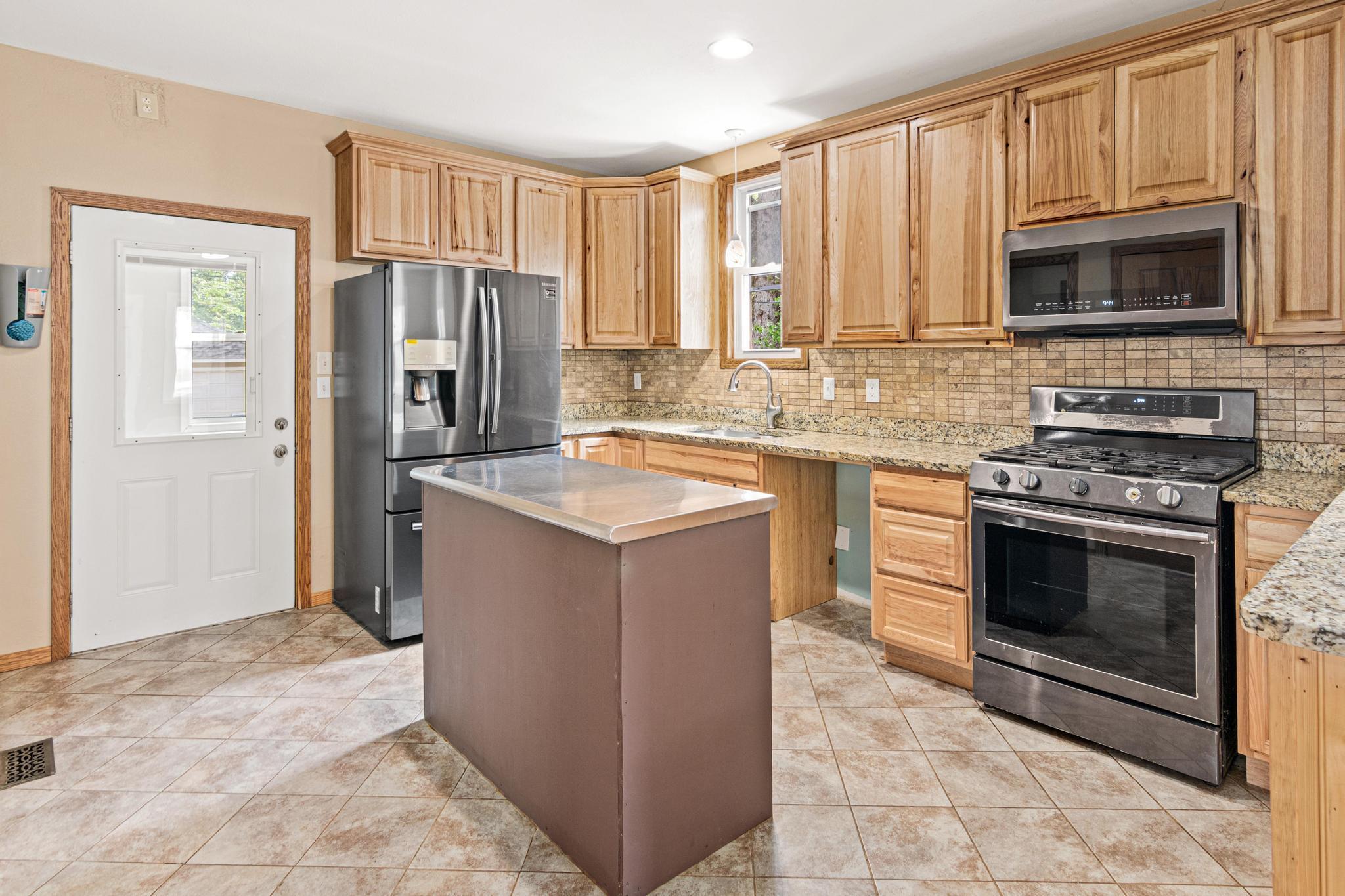 Kitchen features newer refrigerator, microwave, granite countertops, a breakfast bar and high quality cabinets. All set up for dishwasher! Mud room right there too!