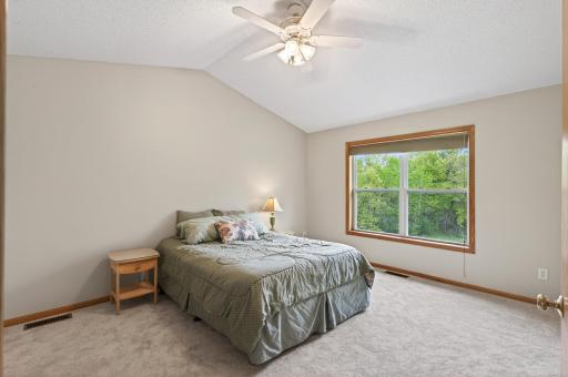 Primary bedroom with vaulted ceilings and fan